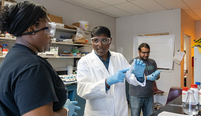 Rajesh Sardar（中）与霍华德大学（Howard University）本科生Omolade Olofintuyi（左）交流，他们针对COVID-19进行先进生物传感器的研究工作。